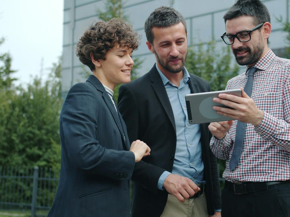 Three colleagues reviewing work on a tablet